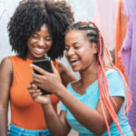 two women holding a phone and laughing