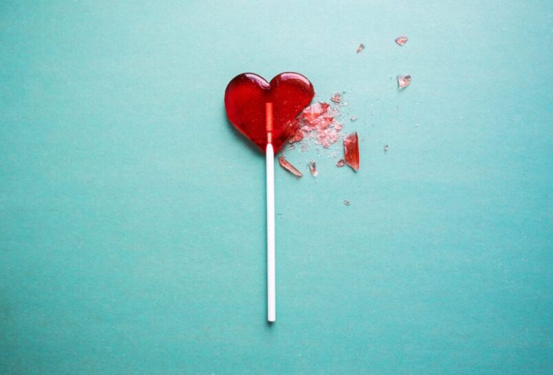 Red heart lollipop broken on blue background