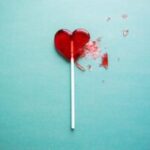 Red heart lollipop broken on blue background