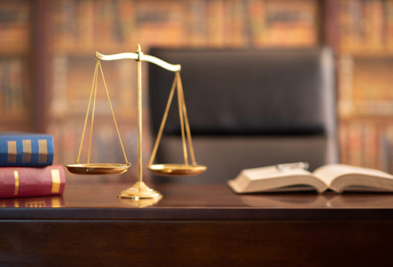 scales of justice on a desk with an open book