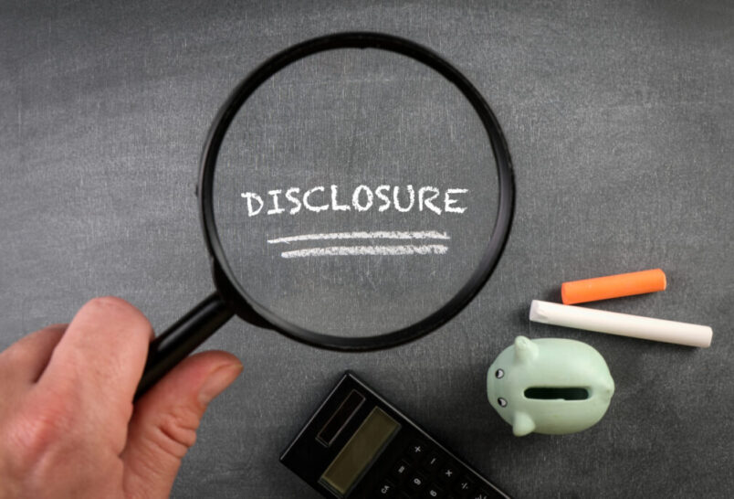 Disclosure text on chalk board under a magnifying glass