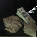 two people shaking hands and holding money