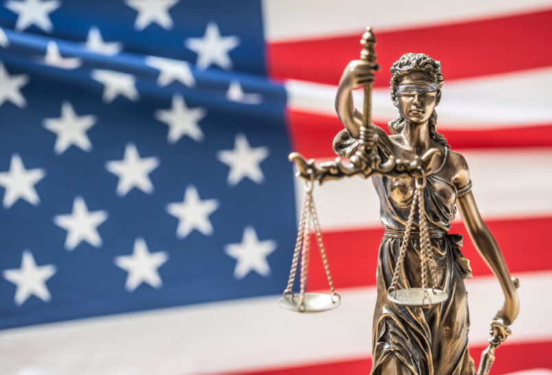 Lady Justice statue in front of american flag