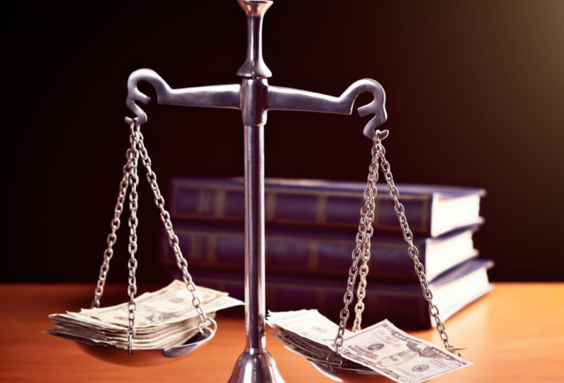 scales of justice are weighted with banknotes